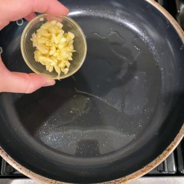 adding garlic to pan for sauce