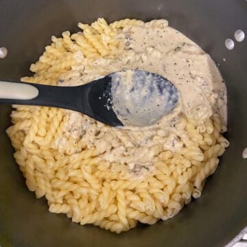 adding cream cheese pasta sauce to pasta 