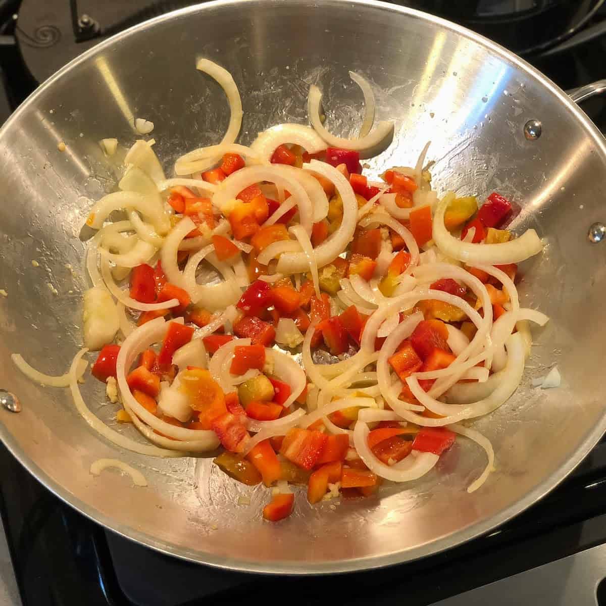 onions, peppers and garlic cooking in pan 