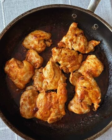 buffalo chicken thighs cooking in pan