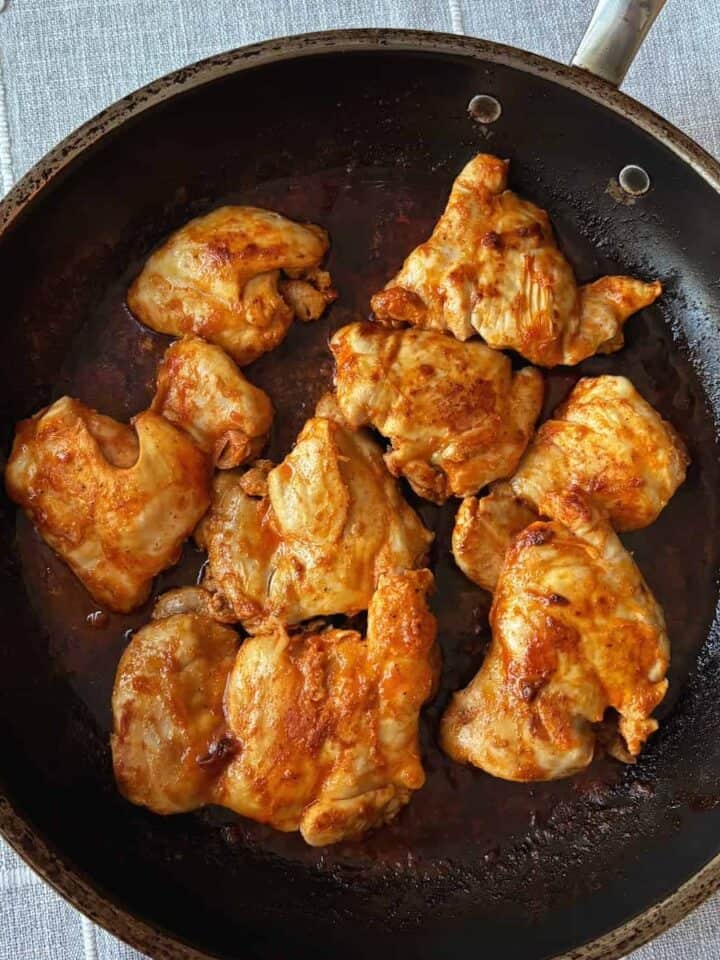 buffalo chicken thighs cooking in pan