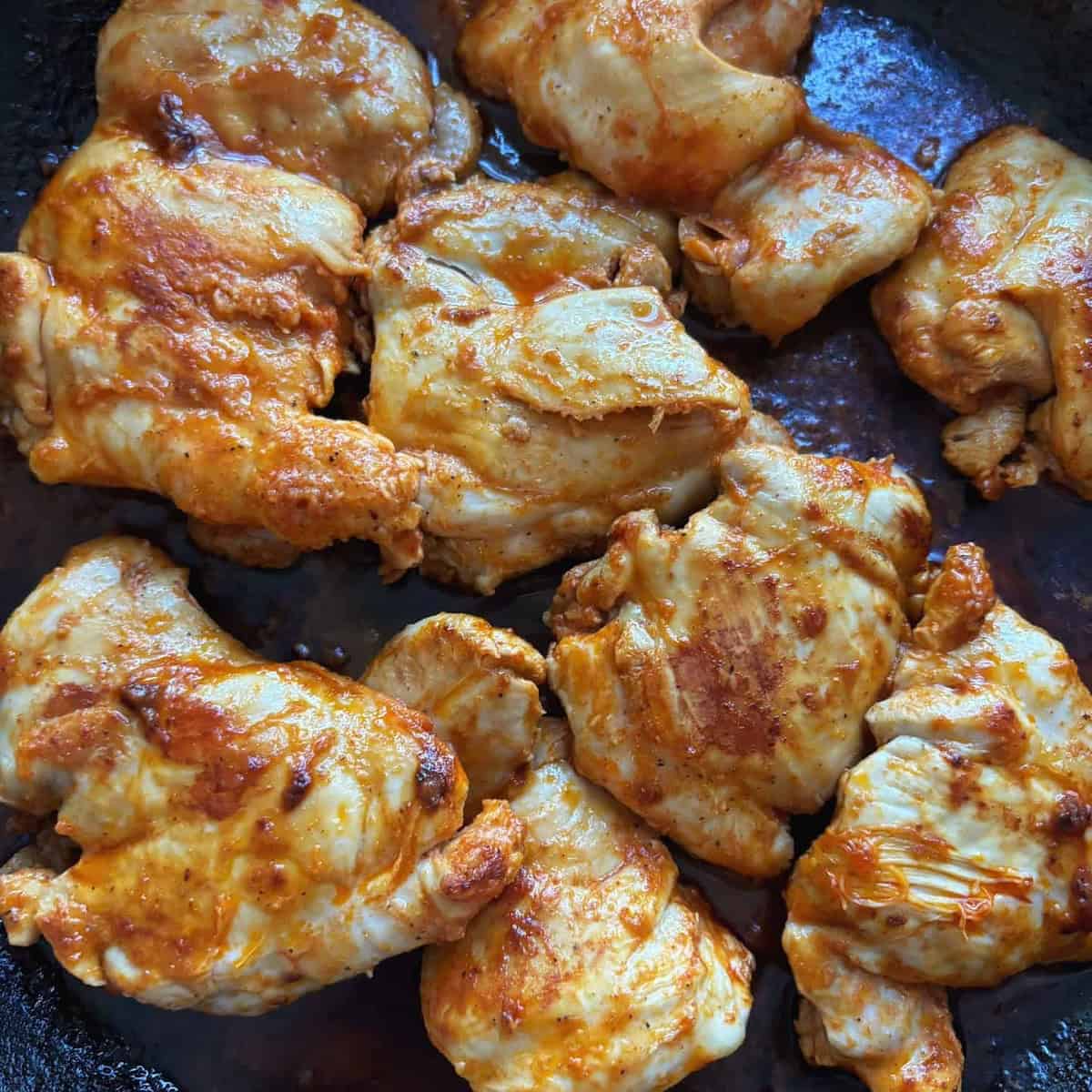 closeup of buffalo chicken thighs fully cooked in pan 