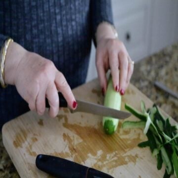 hands slicing cucumber's ends off with a knife 