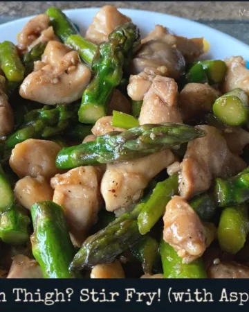 A plate of stir fry chicken thighs and asparagus in a light brown sauce.