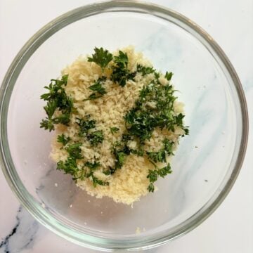 A small bowl with panino breadcrumbs and chopped fresh parsley