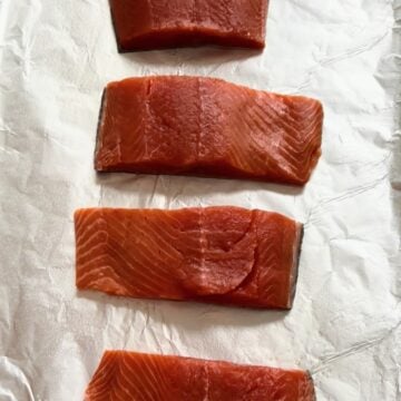 Four raw salmon fillets on tray for honey mustard salmon recipe. 