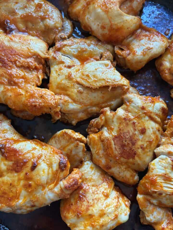 Several buffalo chicken thighs in a pan.