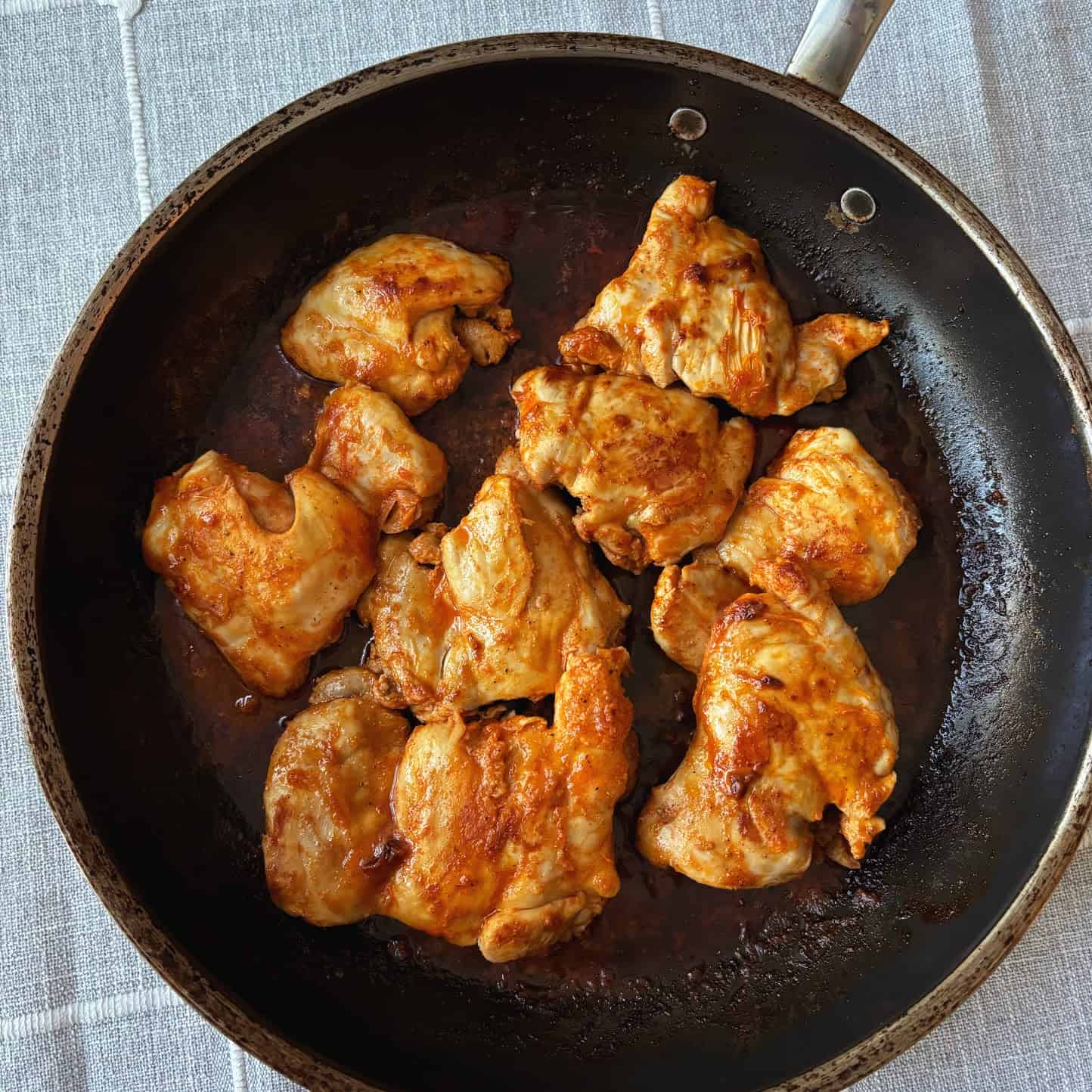 Eight buffalo chicken thighs in a pan. 