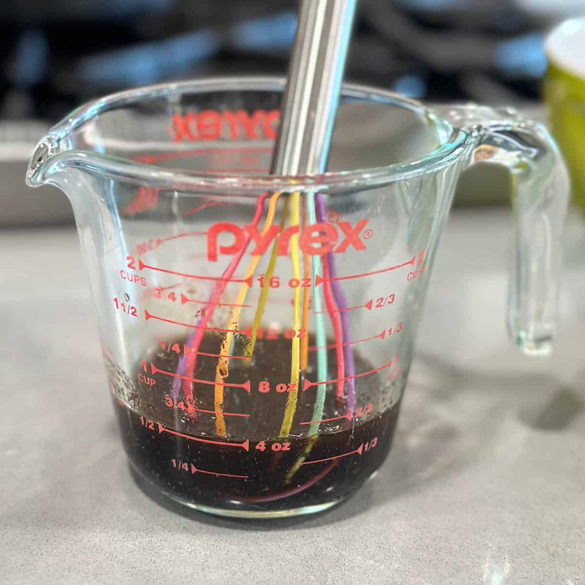 2 cup pyrex of balsamic vinaigrette with rainbow colored whisk