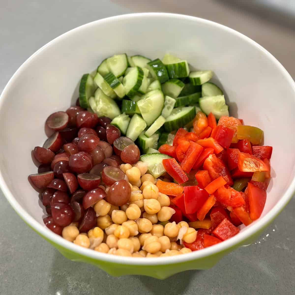 bowl of chickpeas, chopped cucumbers and red bell peppers, and halved grapes
