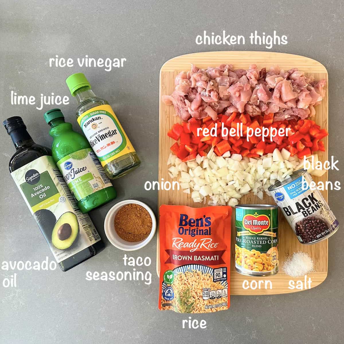 ingredients for a southwest chicken bowl on a wood cutting board and grey countertop