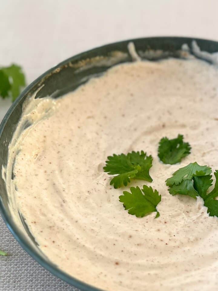 green bowl filled with chipotle crema and cilantro leaves