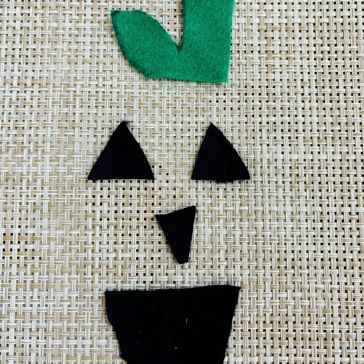 Green stem, black eyes, nose and mouth cut from felt for pumpkin craft. 