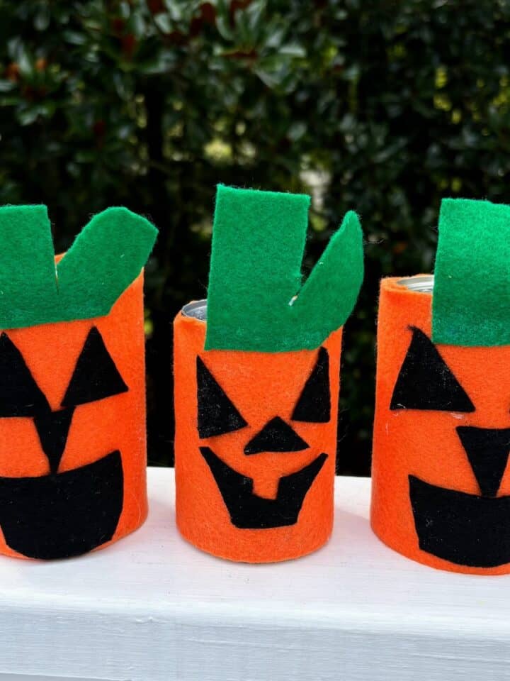 Three tin cans decorated to look like jack-o-lanterns.