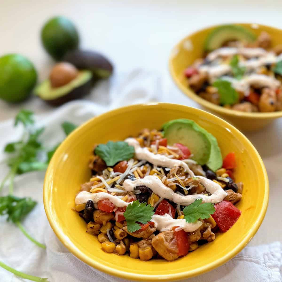 two yellow bowls filled with southwestern chicken and avocado