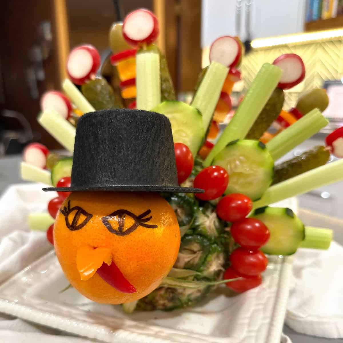 turkey made of orange, pineapple, veggies and tiny hat