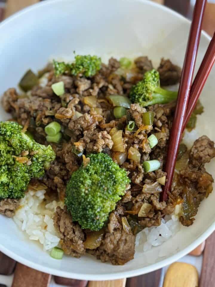 Beef teriyaki rice bowl on brown wooden placemat.