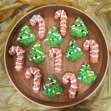candy cane and xmas tree rice krispie treats arranged on a circular wood serving tray