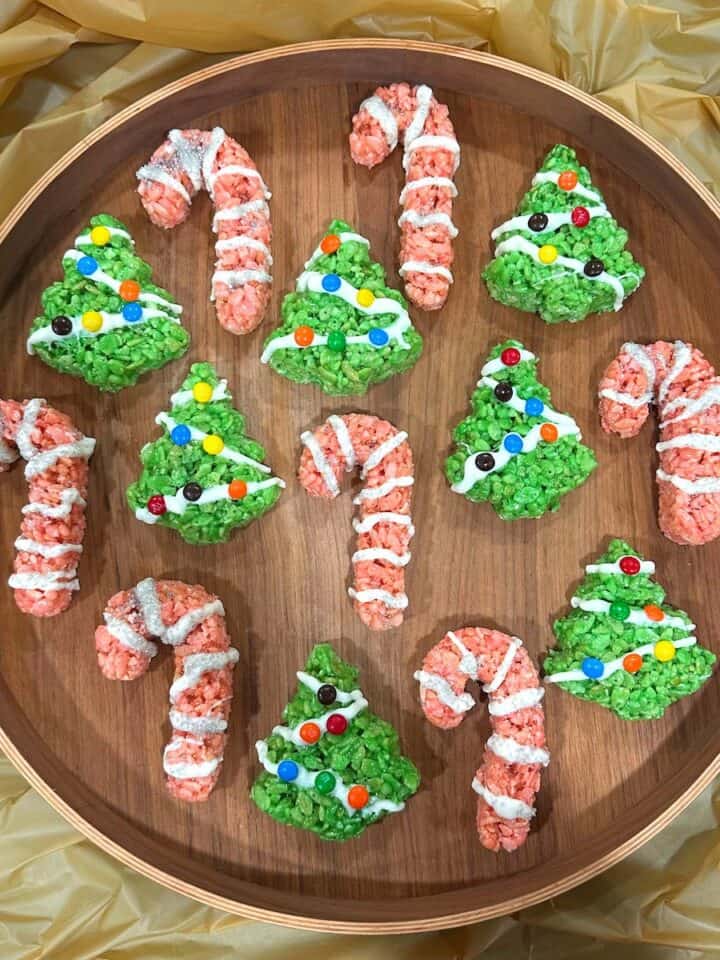 candy cane and xmas tree rice krispie treats arranged on a circular wood serving tray