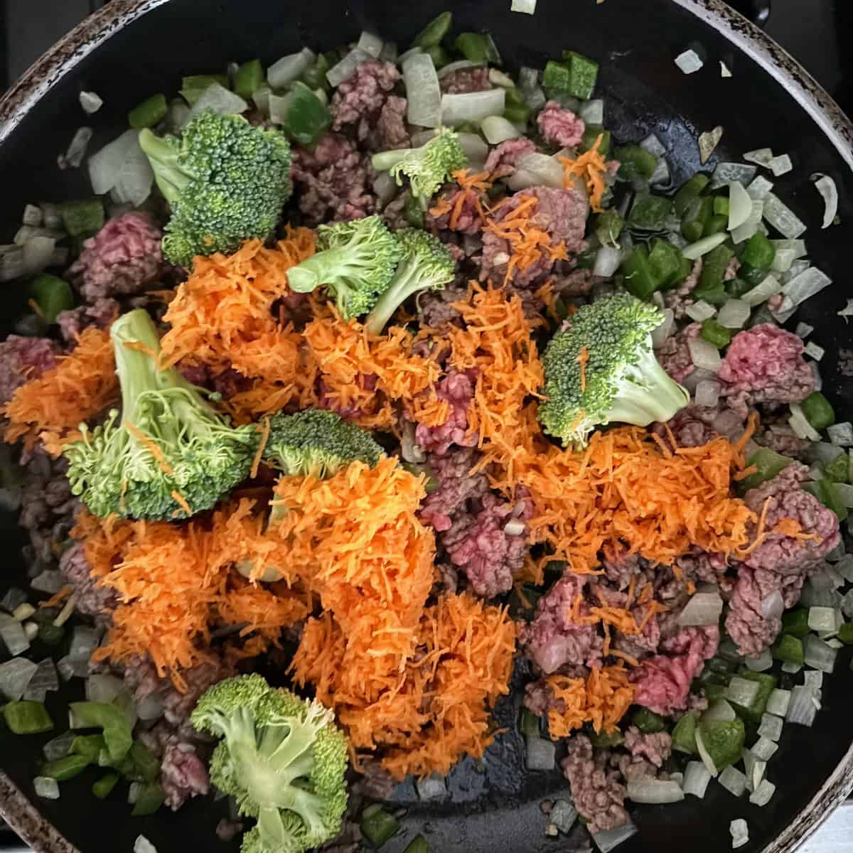 Ground beef and vegetables cooking in pan for beef teriyaki bowl recipe. 