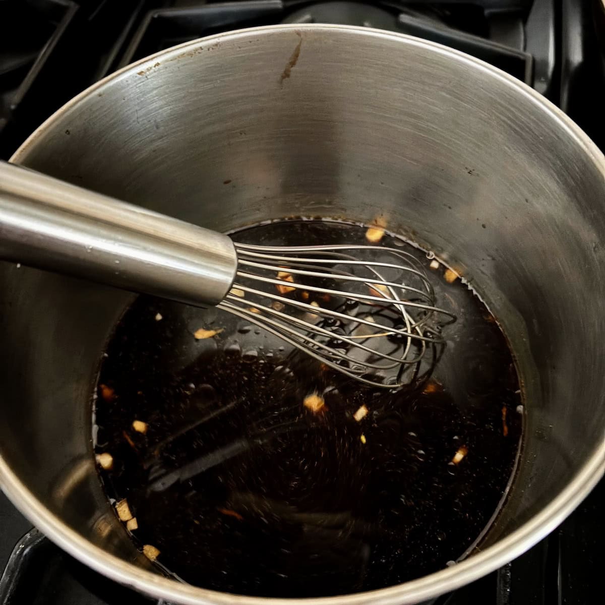 Whisking teriyaki sauce together in sauce pan. 