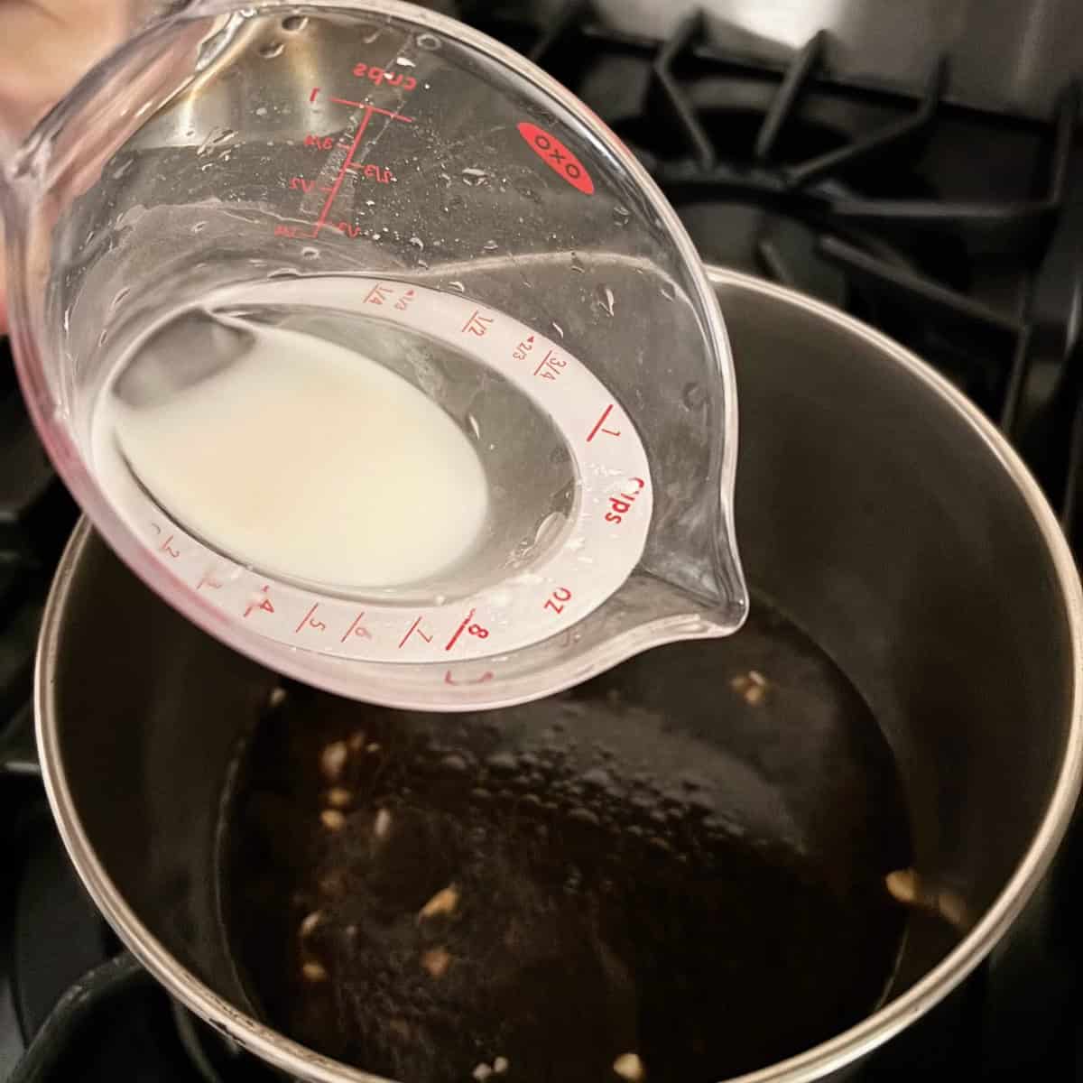 Adding cornstarch with water to the sauce pan. 