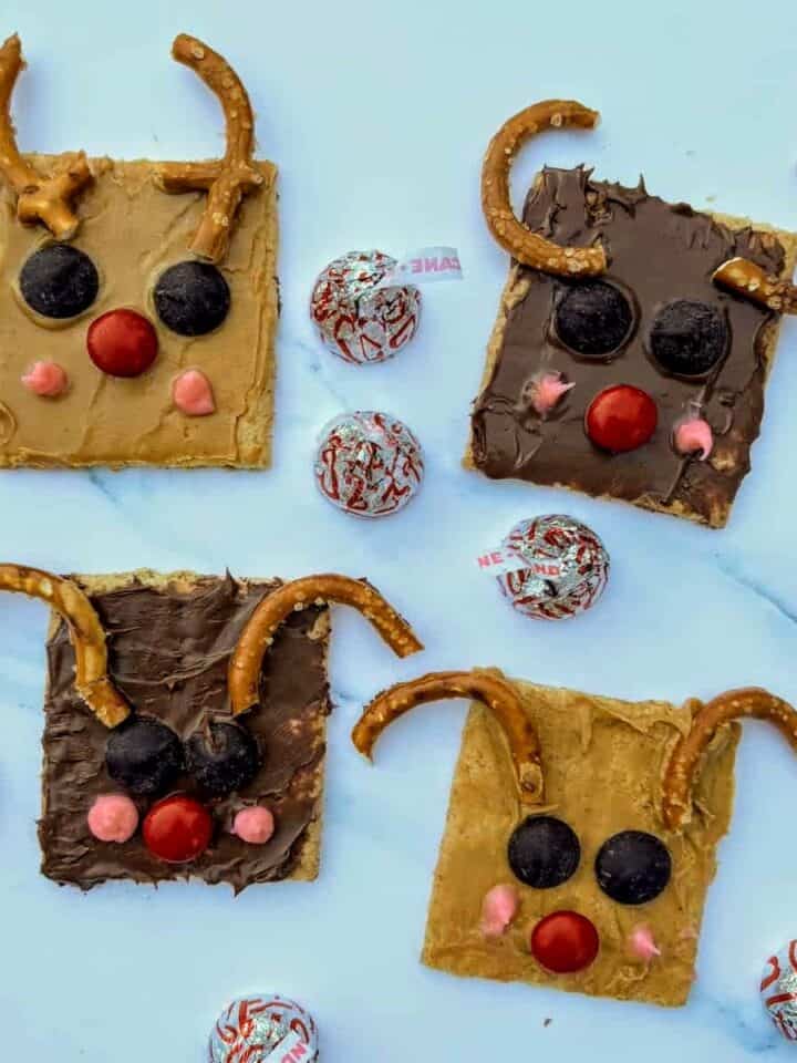 Four reindeer graham crackers with pretzels for ears and candy for eyes and noses.