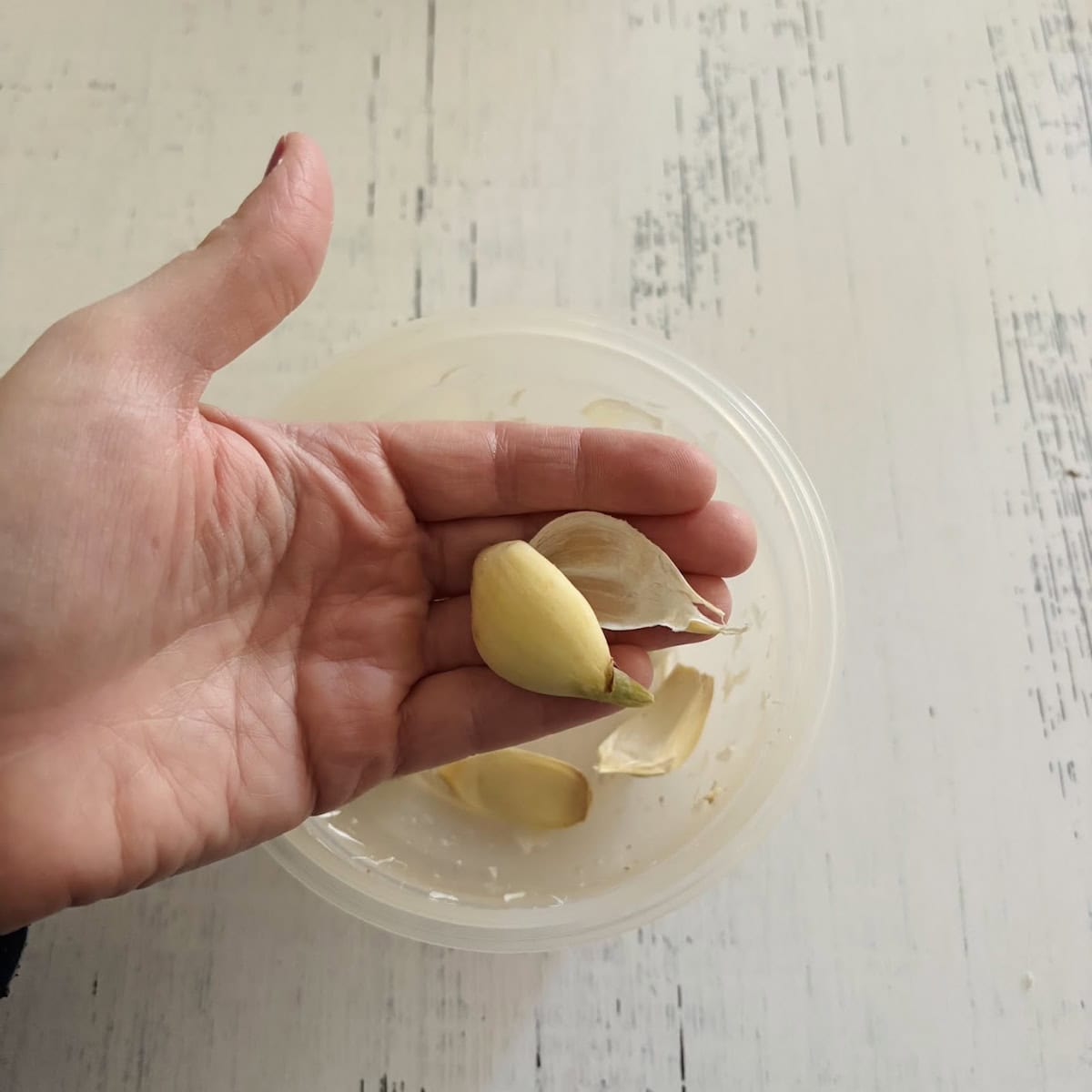 A garlic clove with the skin fallen away in a person's hand. 