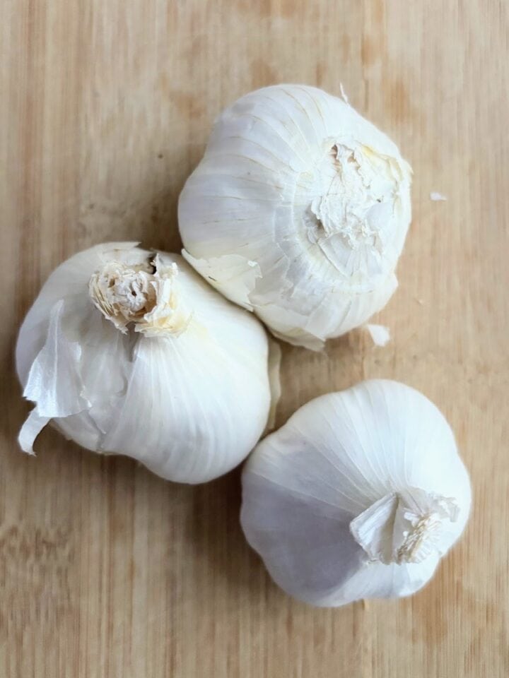 three heads garlic on cutting board