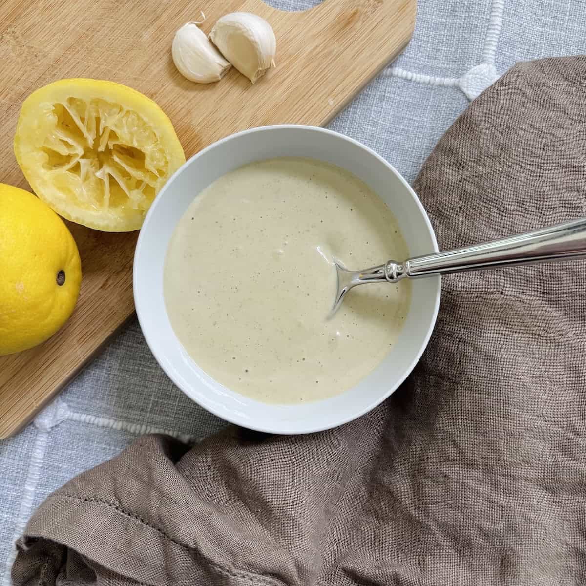 Creamy caesar made with capers in a white bowl and a spoon in the bowl.