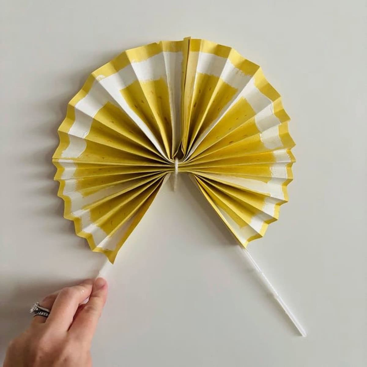 A yellow lemon fan with plastic sticks for handles.