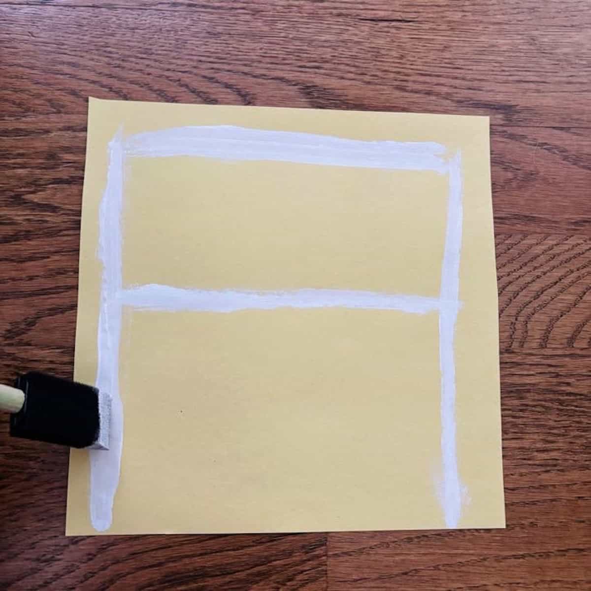 painting white lines on yellow square paper.