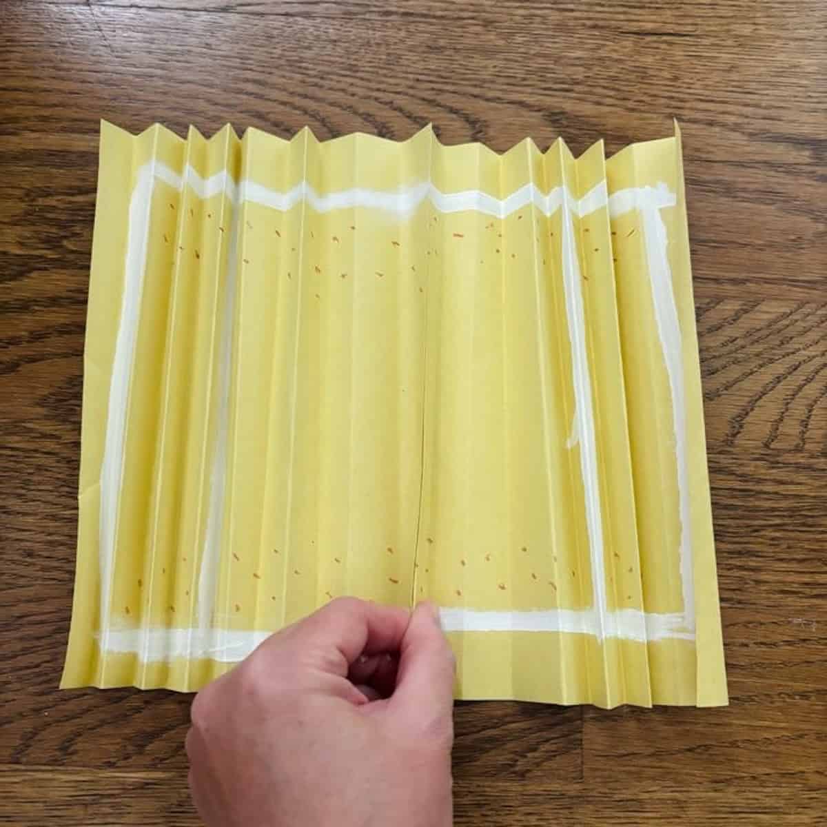 Two yellow accordion folded pieces of paper glued together.