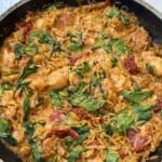 A pan full of chicken orzo with tomatoes and spinach.