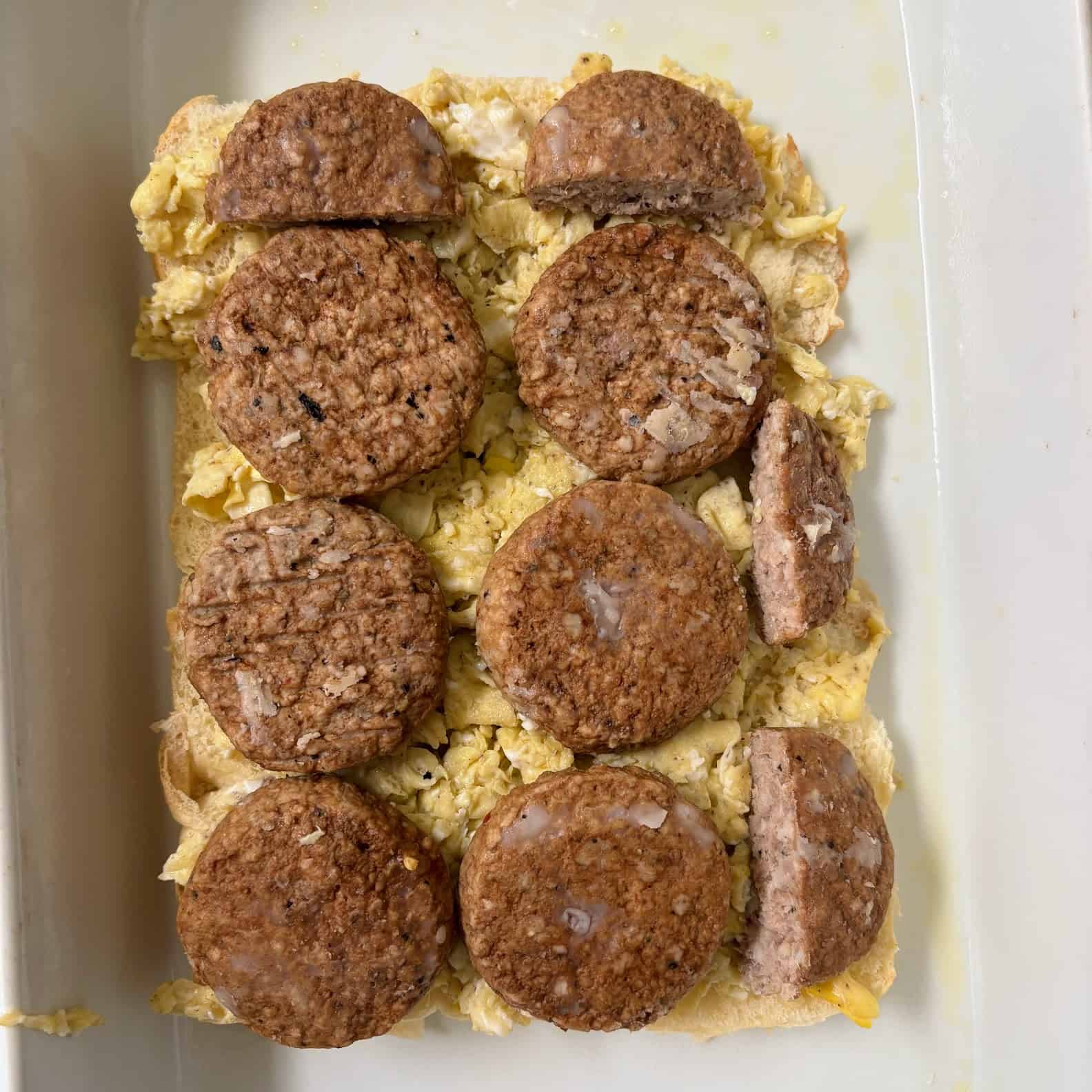Open face breakfast sliders topped with scrambled eggs and sausage patties.