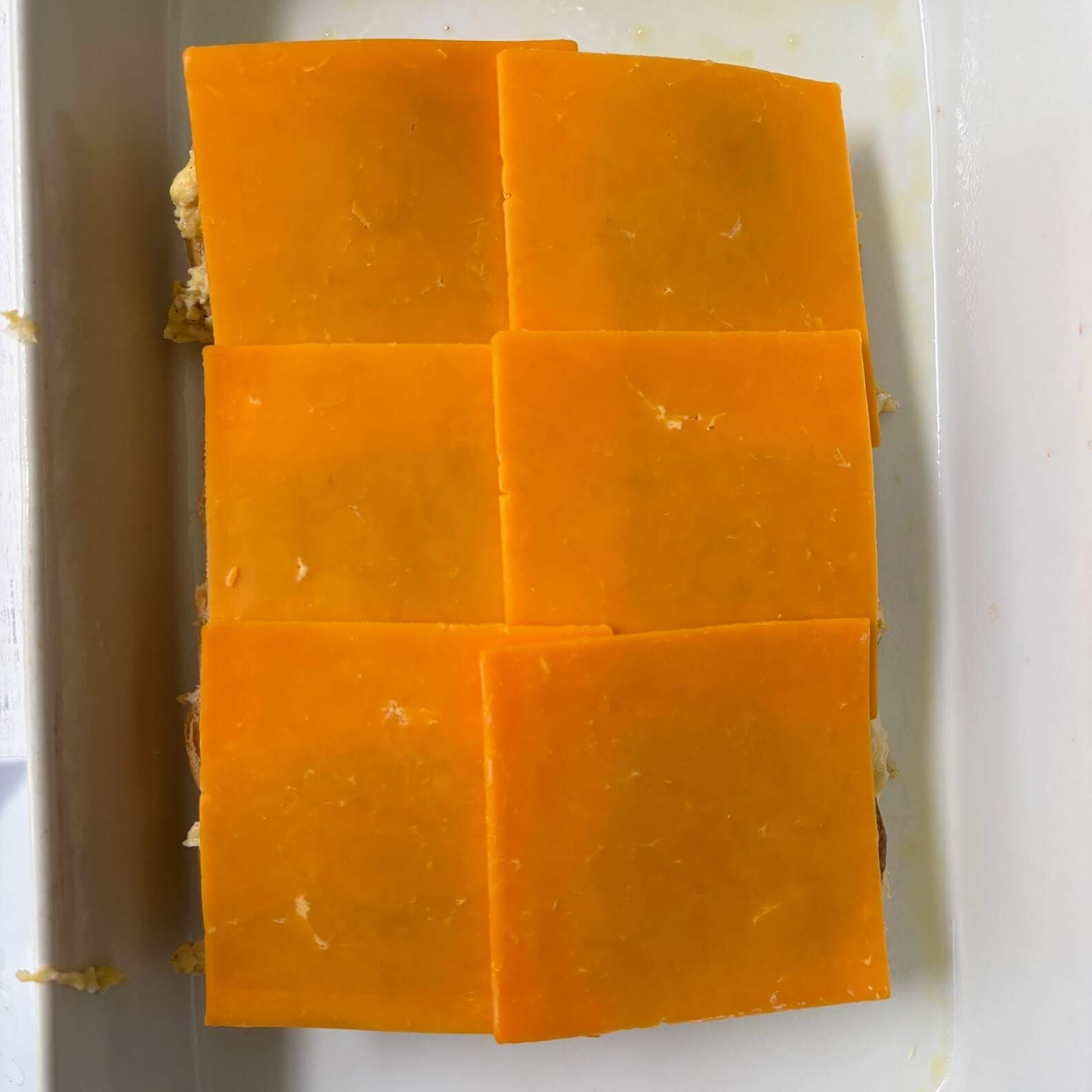 Breakfast sliders topped with square pieces of cheddar cheese.