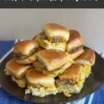 Breakfast sandwiches with sausage, egg and cheese stacked on a black plate.