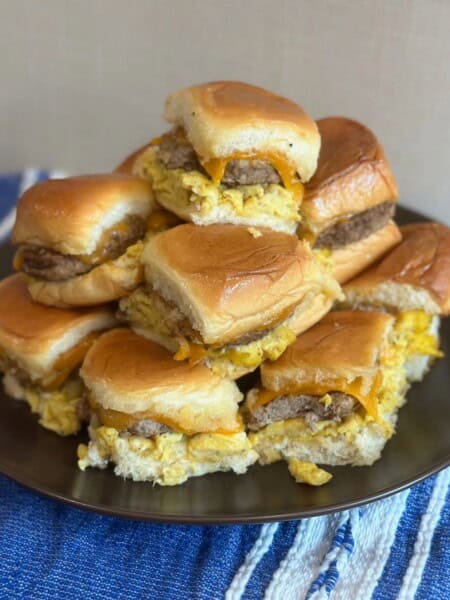 A brown plate filled with stacked sausage, egg and cheese sliders.