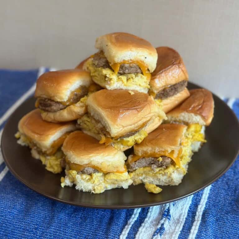 A brown plate filled with stacked sausage, egg and cheese sliders.