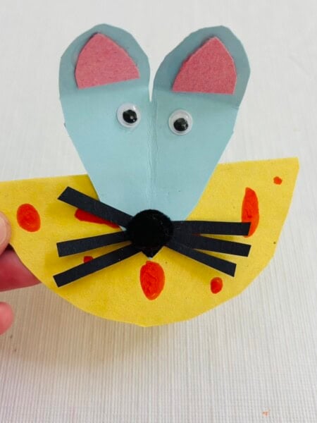 Paper mouse head glued to a yellow piece of paper to look like cheese.
