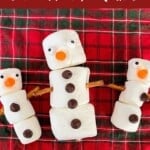 Three showmen made from stringing together marshmallows with stick pretzels and decorated with candy for features, like buttons, a nose and eyes.