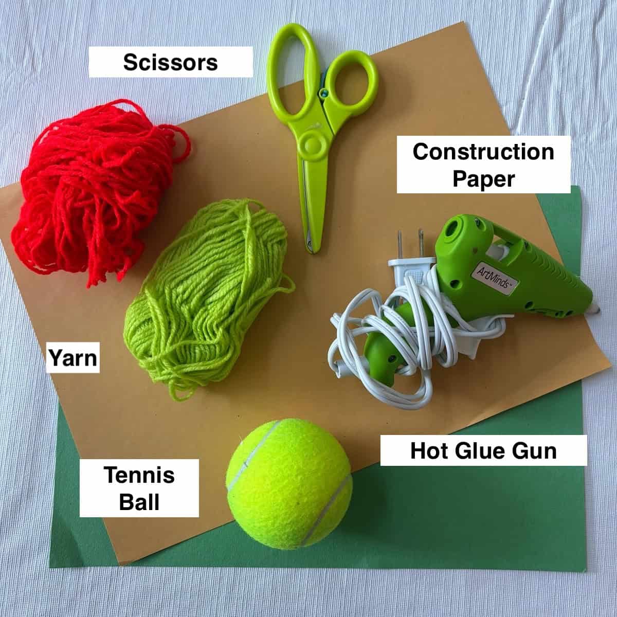 Supplies for the apple craft with tennis ball and yarn.