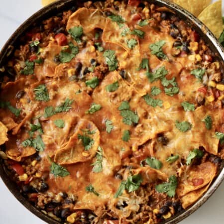 A closeup of an enchilada skillet made with ground turkey, veggies and cheese.