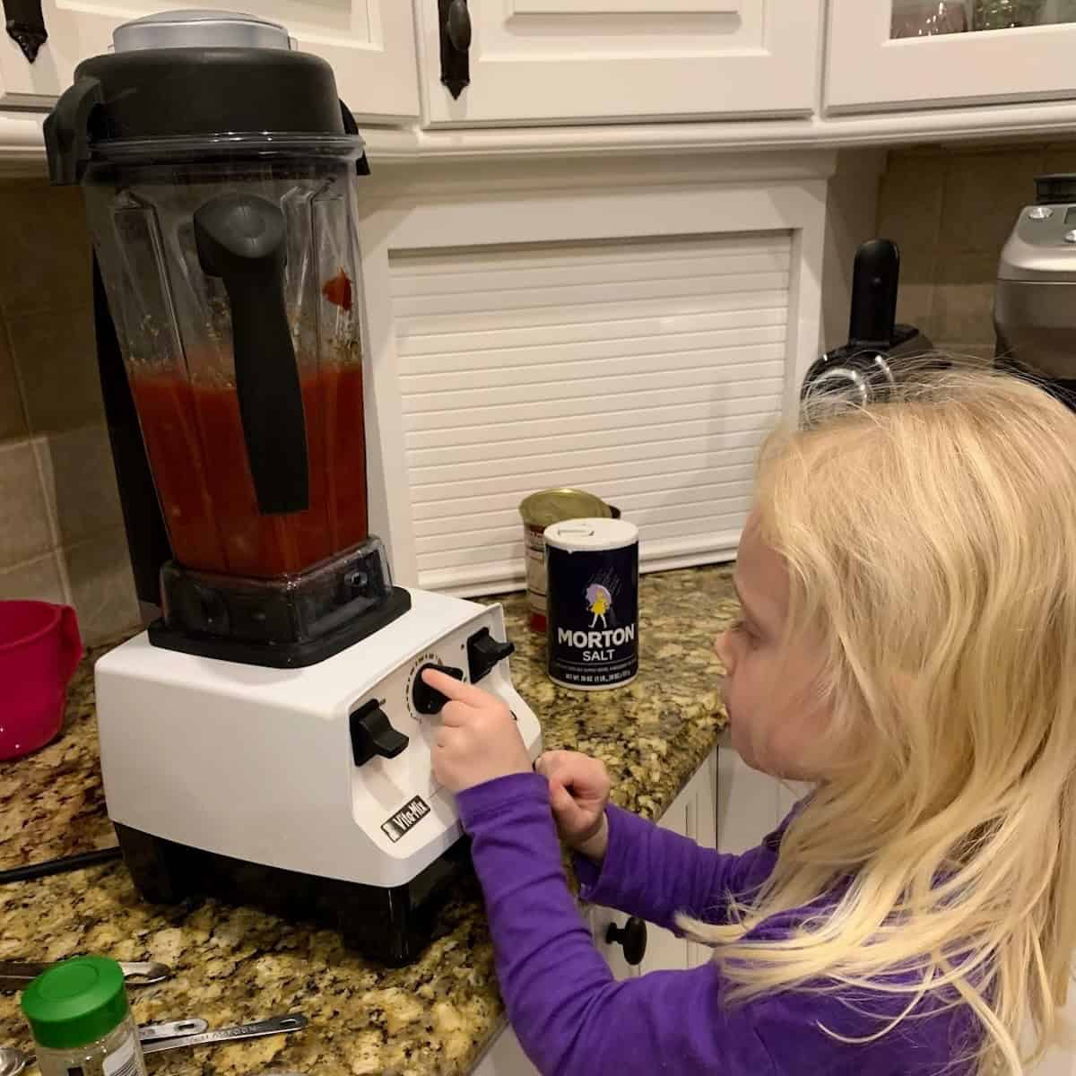 child operating blender to make tomato soup