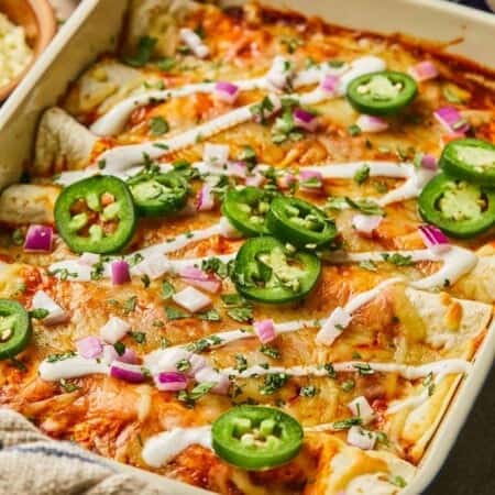 Family-friendly ground turkey enchiladas topped with peppers in a casserole dish.