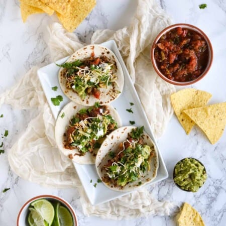 Ground turkey tacos for picky eaters open-faced with toppings on a white plate.
