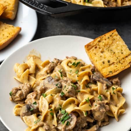 Ground turkey stroganoff on a white plate with a side of bread.