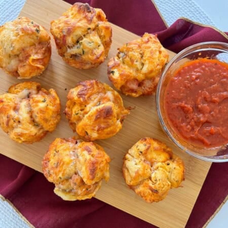 Pizza muffins made with biscuits served with side of marinara sauce.