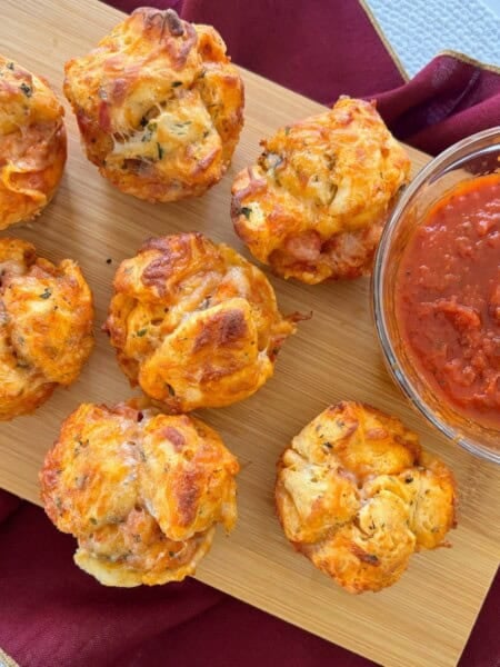 Pizza muffins made with biscuits served with side of marinara sauce.