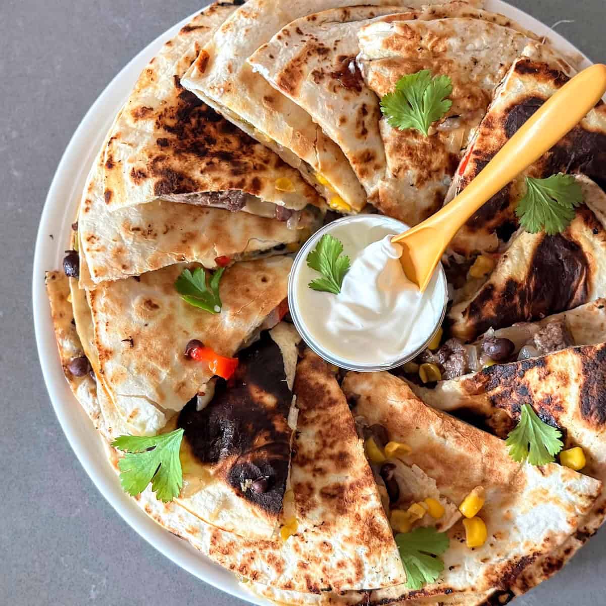 Full spread of s crispy steak quesadillas with sour cream